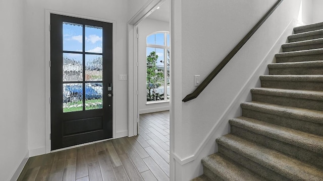 foyer featuring baseboards, stairway, and dark wood finished floors