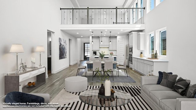 living room with a high ceiling, baseboards, and wood finished floors