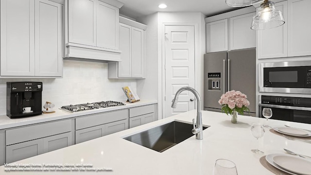 kitchen featuring light countertops, appliances with stainless steel finishes, a sink, and custom range hood