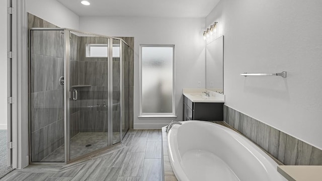 bathroom featuring a garden tub, a shower stall, and vanity