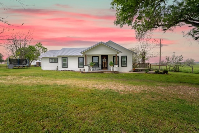 view of front of home with a lawn, a porch, and a trampoline