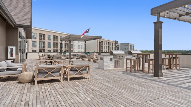 wooden terrace featuring outdoor lounge area, a pergola, an outdoor kitchen, and grilling area