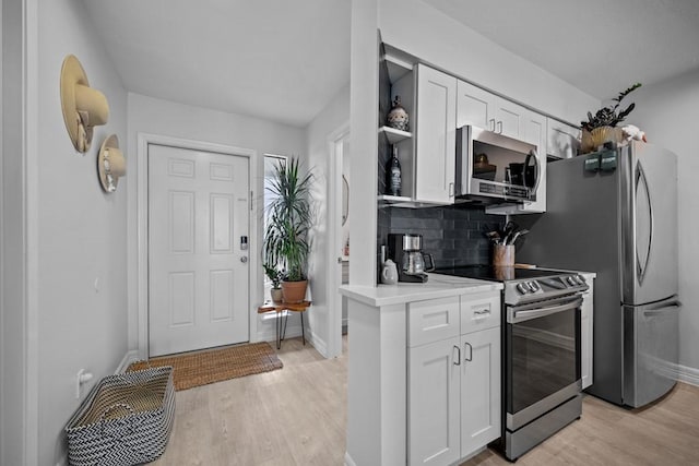 kitchen featuring tasteful backsplash, stainless steel appliances, light hardwood / wood-style floors, and white cabinets