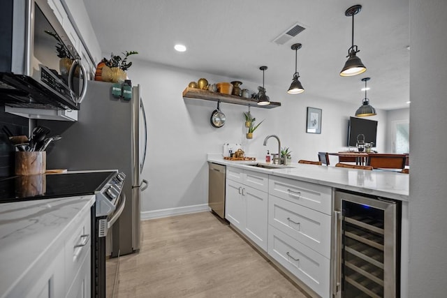 kitchen featuring appliances with stainless steel finishes, decorative light fixtures, sink, white cabinets, and wine cooler