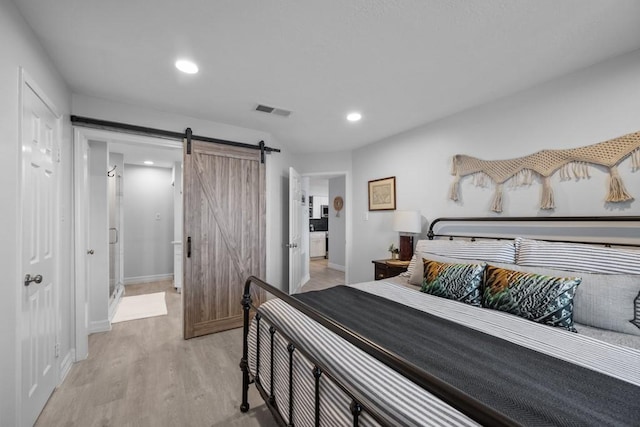 bedroom with a barn door and light wood-type flooring