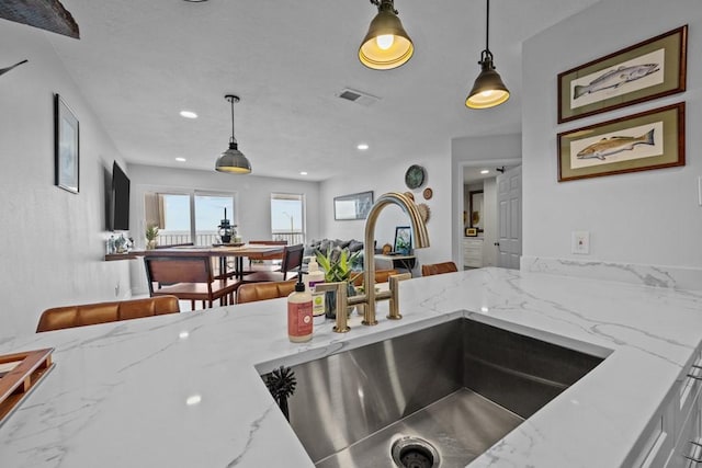 kitchen featuring sink, pendant lighting, and light stone counters