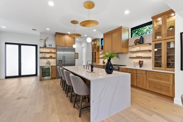 kitchen with plenty of natural light, high end fridge, wine cooler, and hanging light fixtures