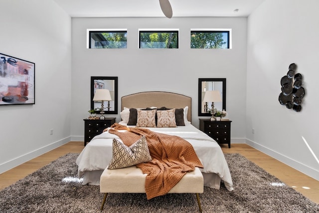 bedroom featuring ceiling fan, light hardwood / wood-style floors, and multiple windows