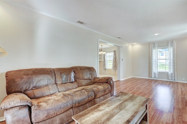 living room featuring light hardwood / wood-style flooring, a notable chandelier, and ornamental molding