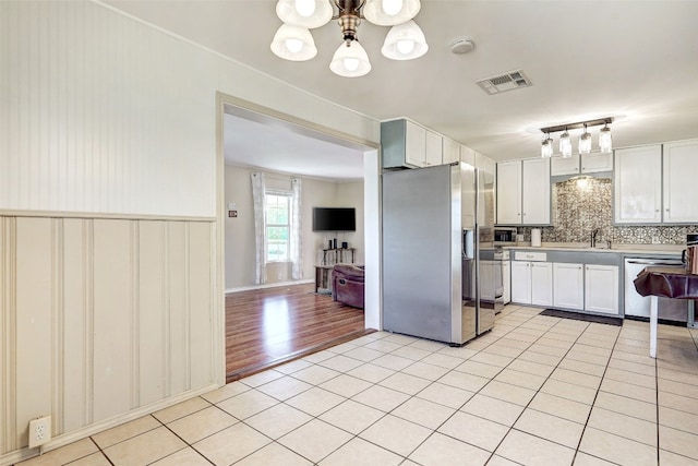 kitchen featuring an inviting chandelier, light hardwood / wood-style floors, tasteful backsplash, stainless steel appliances, and pendant lighting