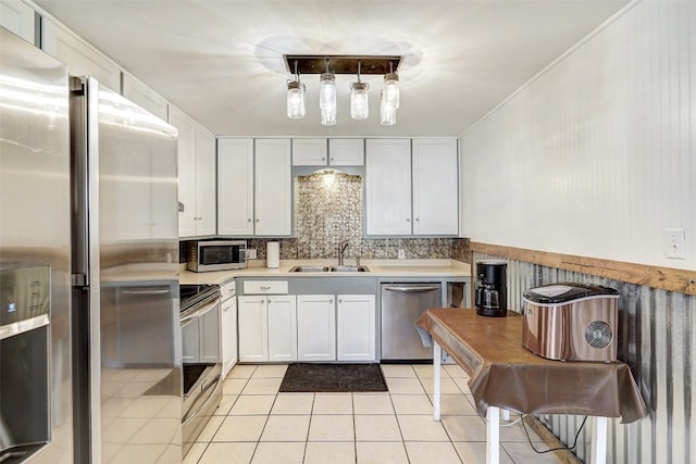 kitchen featuring sink, light tile floors, backsplash, stainless steel appliances, and white cabinetry