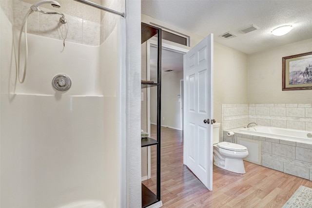 bathroom featuring toilet, plus walk in shower, hardwood / wood-style floors, and a textured ceiling