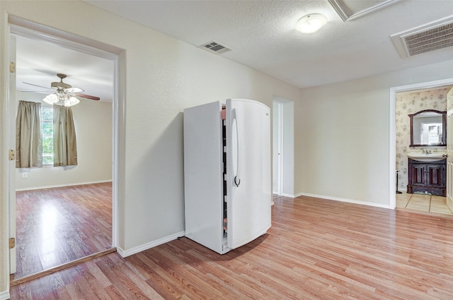 interior space with a textured ceiling, ceiling fan, light wood-type flooring, and sink