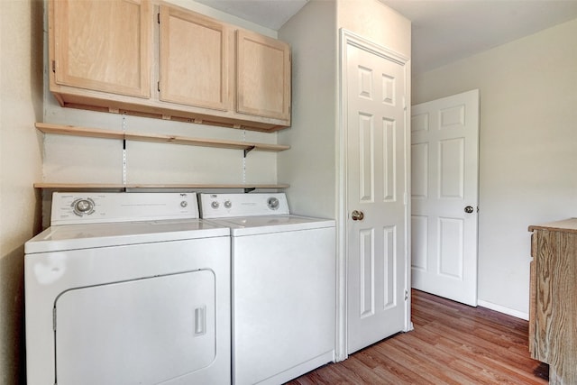 laundry area with cabinets, light hardwood / wood-style floors, and washing machine and clothes dryer