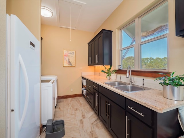 kitchen featuring light stone countertops, sink, light tile floors, washer and dryer, and white refrigerator