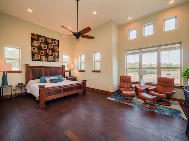 bedroom with a high ceiling, ceiling fan, multiple windows, and dark hardwood / wood-style flooring