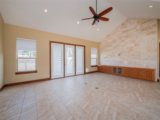 empty room with ceiling fan, high vaulted ceiling, and light tile floors