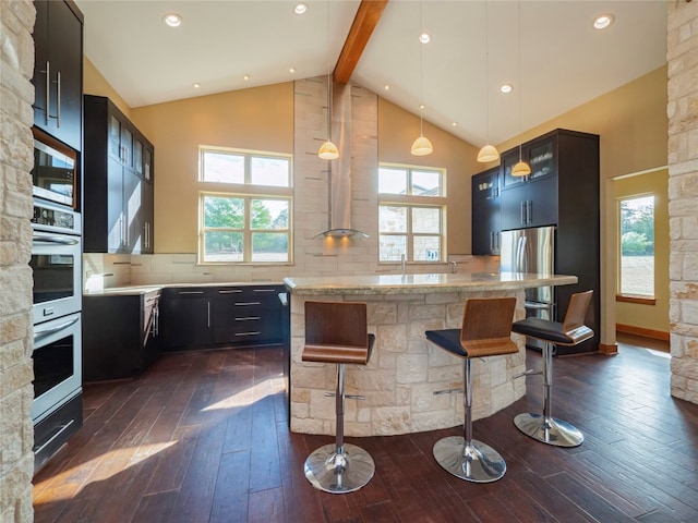 kitchen with hanging light fixtures, beamed ceiling, dark wood-type flooring, backsplash, and a kitchen breakfast bar