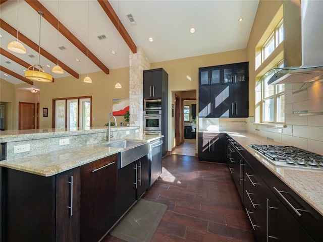 kitchen featuring a wealth of natural light, beamed ceiling, wall chimney exhaust hood, backsplash, and hanging light fixtures