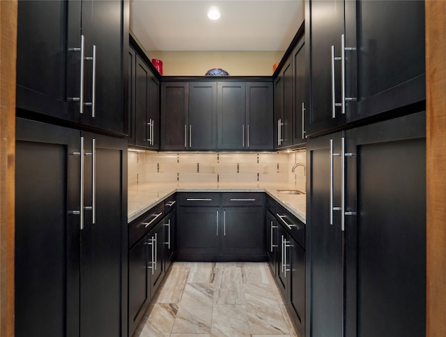 kitchen featuring sink, backsplash, light stone counters, and light tile flooring