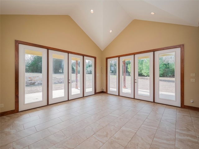 unfurnished room with high vaulted ceiling, a healthy amount of sunlight, light tile floors, and french doors