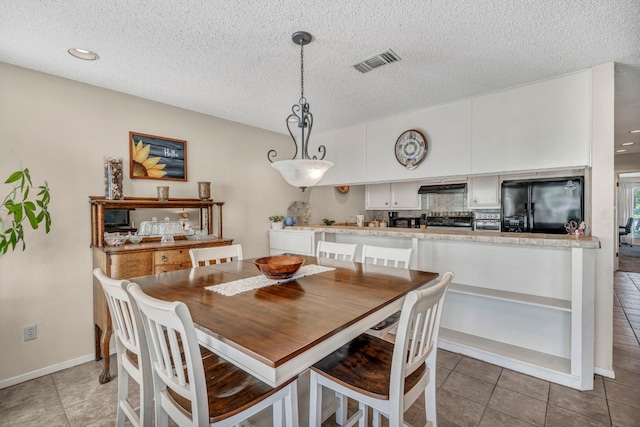 dining space with light tile flooring and a textured ceiling