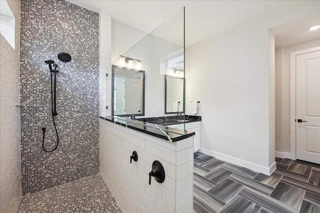 full bath featuring baseboards, walk in shower, and vanity