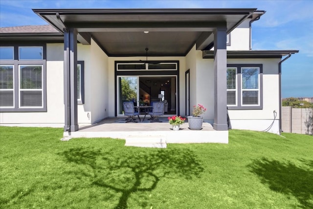 rear view of property featuring a patio, a lawn, and stucco siding