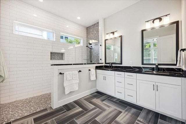 bathroom with a healthy amount of sunlight, double vanity, walk in shower, and a sink