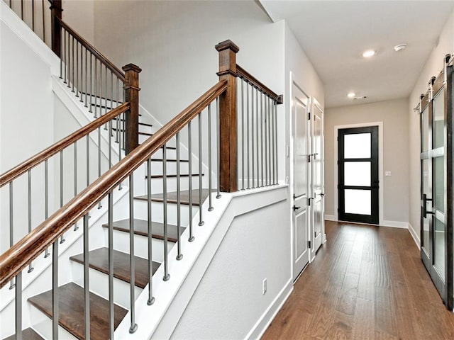 foyer entrance featuring a barn door, baseboards, dark wood-type flooring, and recessed lighting