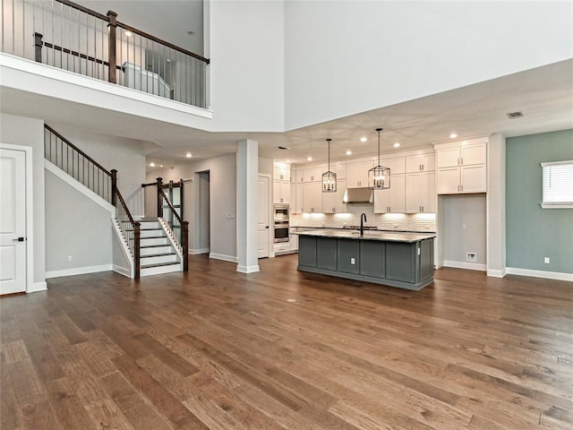 unfurnished living room featuring recessed lighting, visible vents, baseboards, stairs, and dark wood-style floors