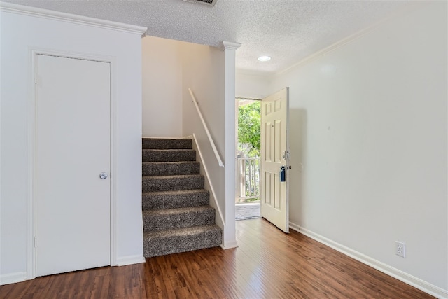 stairs with a textured ceiling, ornamental molding, and hardwood / wood-style floors