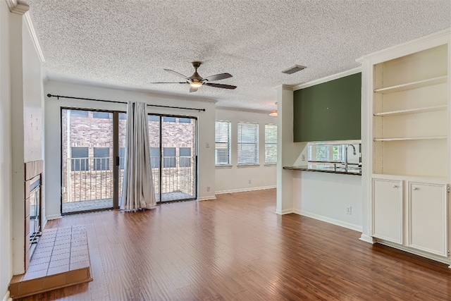 unfurnished living room with crown molding, a textured ceiling, and hardwood / wood-style floors