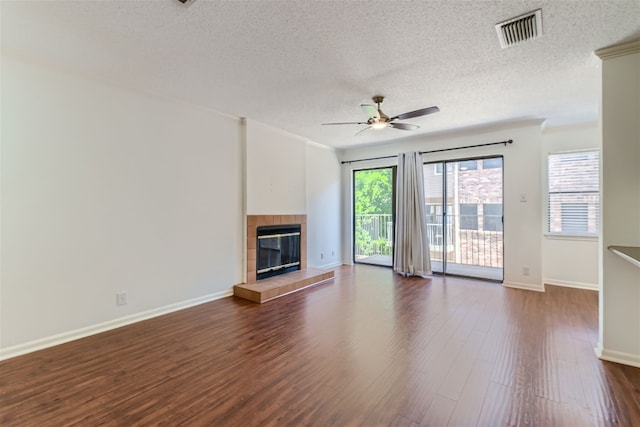 unfurnished living room featuring a textured ceiling, dark wood-type flooring, ceiling fan, and a fireplace