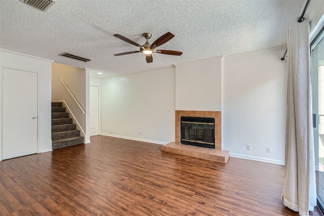 unfurnished living room with a textured ceiling, a tile fireplace, ceiling fan, and wood-type flooring