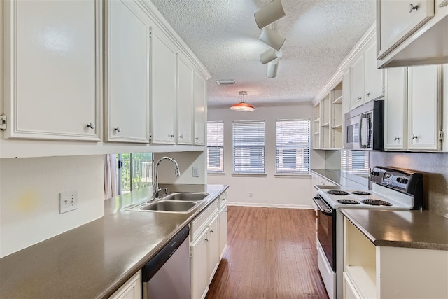 kitchen featuring stainless steel appliances, white cabinetry, sink, dark wood-type flooring, and a textured ceiling