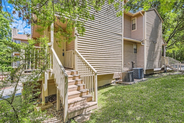 view of property exterior with central AC unit and a lawn