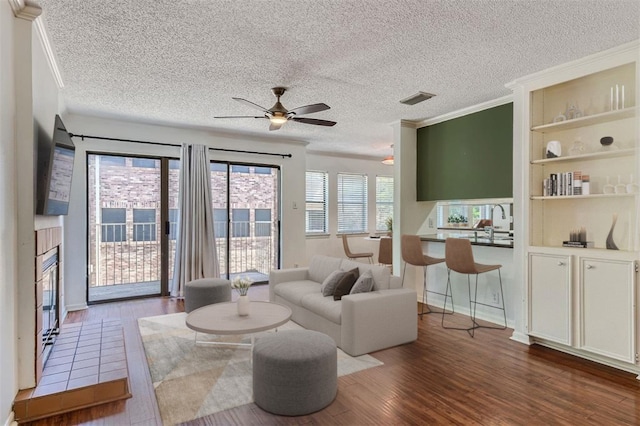 living room featuring a textured ceiling, a tiled fireplace, and wood-type flooring