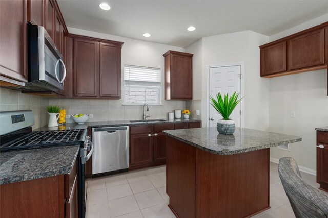 kitchen featuring light tile flooring, appliances with stainless steel finishes, backsplash, dark stone countertops, and sink