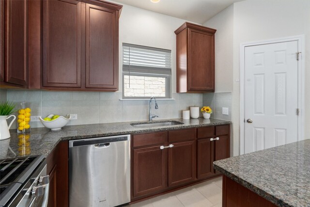 kitchen featuring dark stone counters, backsplash, light tile floors, dishwasher, and sink