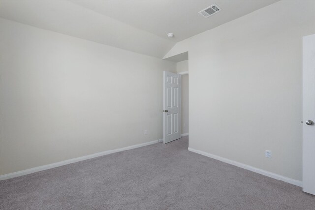 carpeted spare room with vaulted ceiling