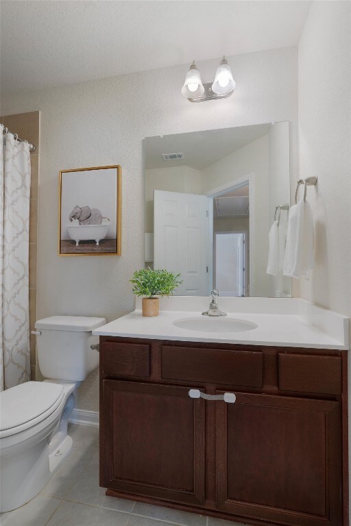 bathroom featuring tile flooring, toilet, and vanity