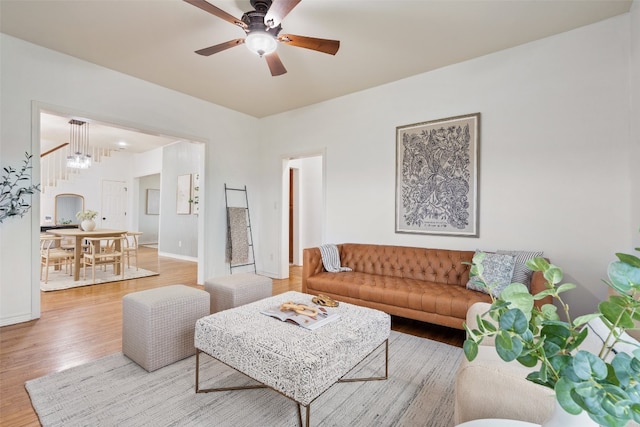 living room with light hardwood / wood-style flooring and ceiling fan with notable chandelier