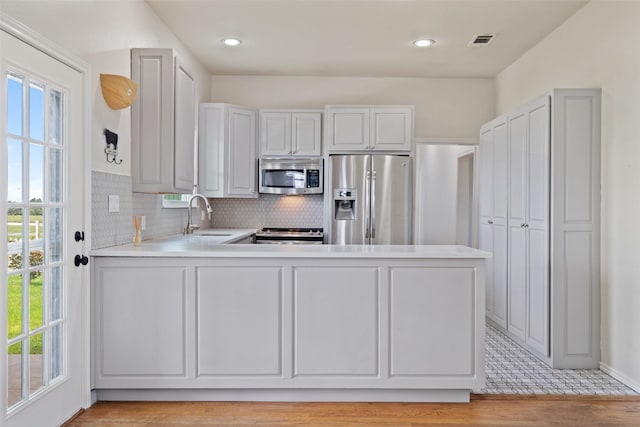 kitchen with appliances with stainless steel finishes, plenty of natural light, kitchen peninsula, and sink