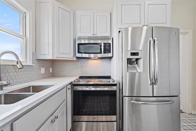 kitchen with appliances with stainless steel finishes, tasteful backsplash, white cabinetry, and sink