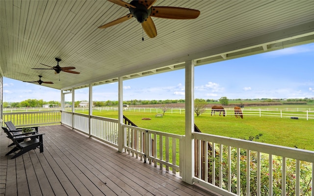 wooden terrace featuring ceiling fan, a yard, and a rural view