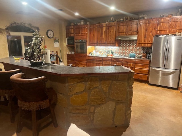 409 County Road 138th Rd, Burnet, TX 78611 - kitchen with a breakfast bar, ventilation hood, backsplash, appliances with stainless steel finishes, and brown cabinets