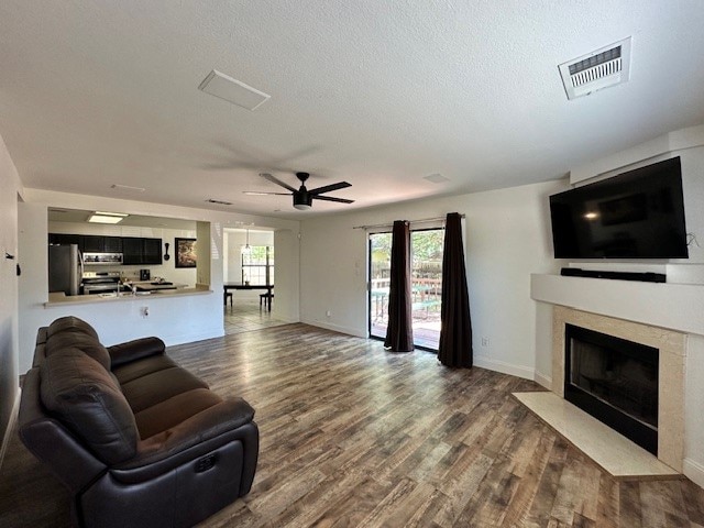 living room featuring a textured ceiling, a high end fireplace, ceiling fan, and hardwood / wood-style floors