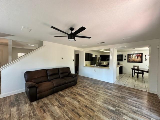 living room with a textured ceiling, ceiling fan, and hardwood / wood-style floors