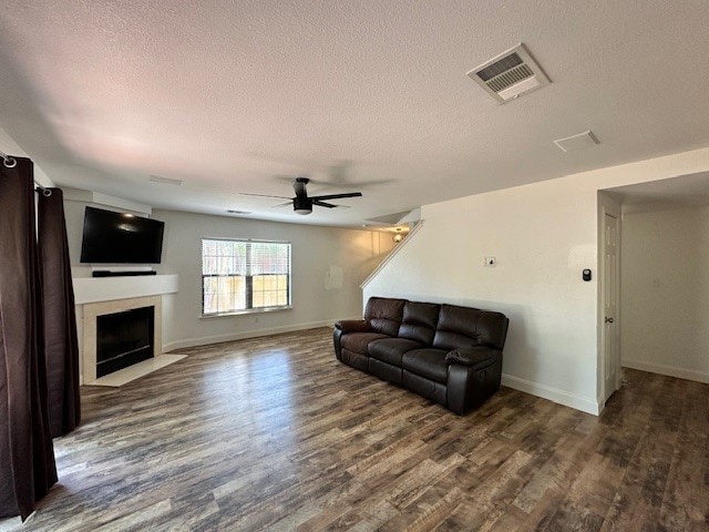 living room with ceiling fan, dark hardwood / wood-style flooring, and a textured ceiling